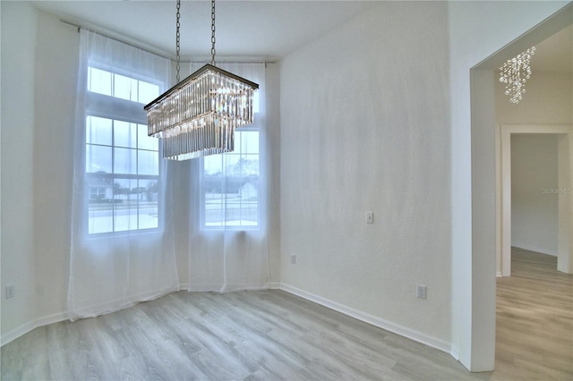 unfurnished dining area featuring a notable chandelier and light hardwood / wood-style floors