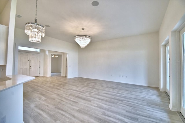 unfurnished living room featuring a chandelier and light hardwood / wood-style floors