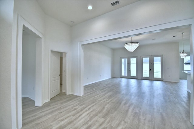 unfurnished room featuring a chandelier and light hardwood / wood-style floors