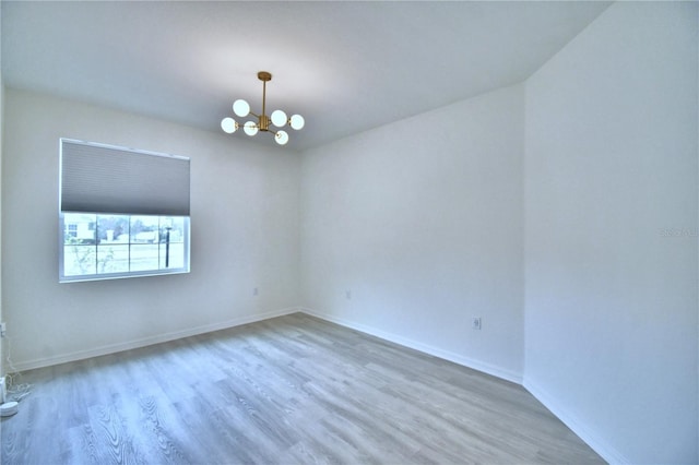 spare room featuring hardwood / wood-style floors and a notable chandelier