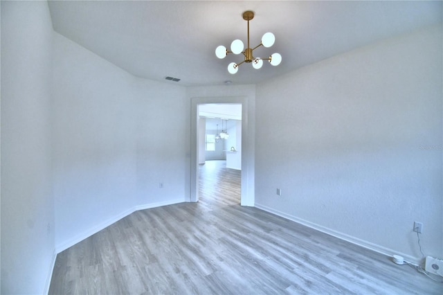 spare room with hardwood / wood-style floors and a notable chandelier