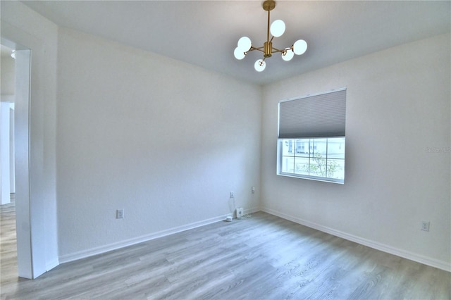 empty room with wood-type flooring and a chandelier