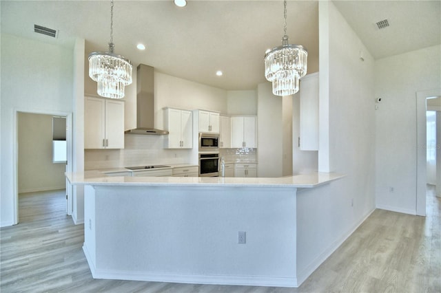 kitchen with decorative light fixtures, white cabinets, a chandelier, and wall chimney exhaust hood