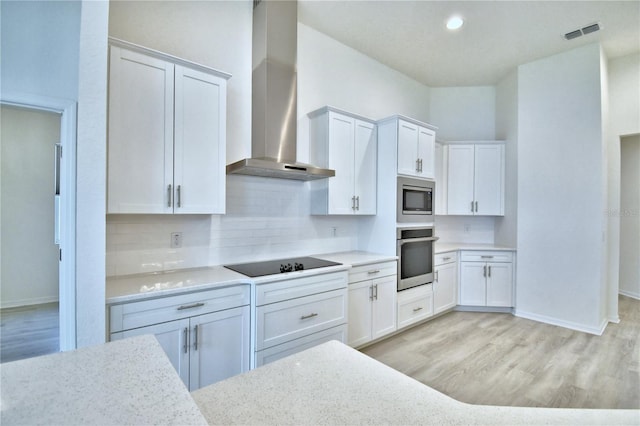 kitchen featuring white cabinets, light hardwood / wood-style floors, wall chimney exhaust hood, and appliances with stainless steel finishes