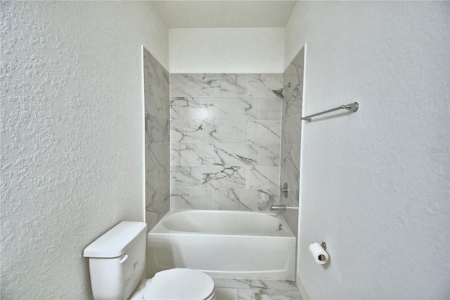 bathroom with tiled shower / bath combo and toilet