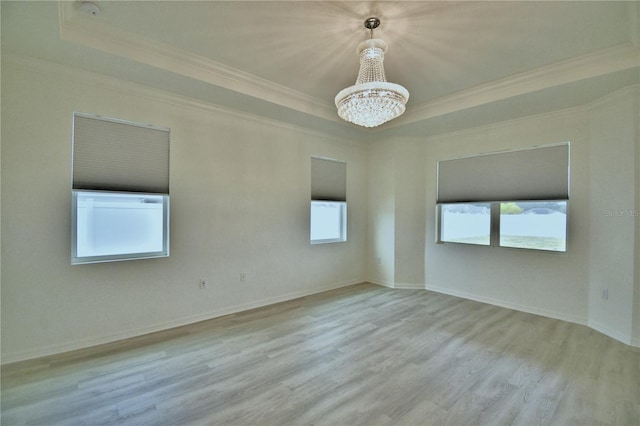 spare room with crown molding, light hardwood / wood-style flooring, a raised ceiling, and a chandelier