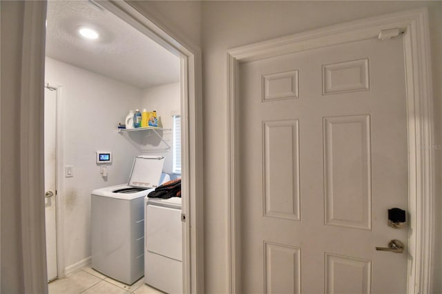 clothes washing area with light tile patterned floors and washer and clothes dryer