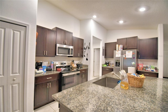 kitchen featuring lofted ceiling, sink, stainless steel appliances, and stone countertops