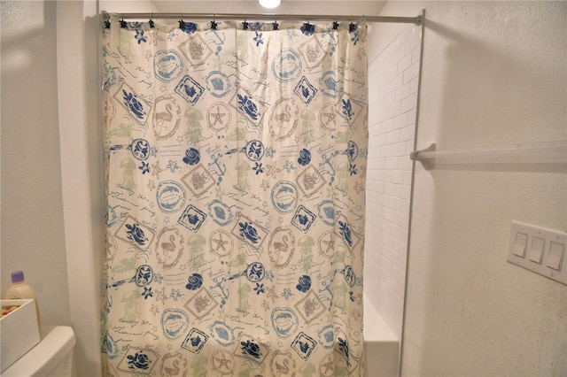 bathroom with shower / bath combination with curtain and toilet