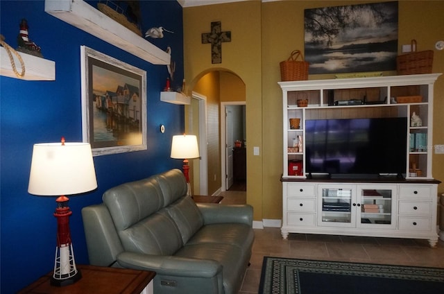 living area featuring baseboards, arched walkways, and dark tile patterned flooring