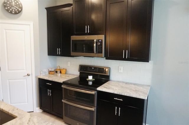 kitchen featuring decorative backsplash, light stone counters, and appliances with stainless steel finishes