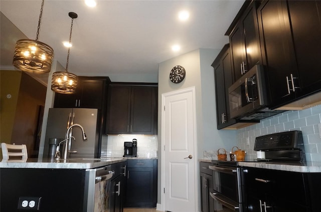 kitchen featuring tasteful backsplash, decorative light fixtures, appliances with stainless steel finishes, and a kitchen island with sink