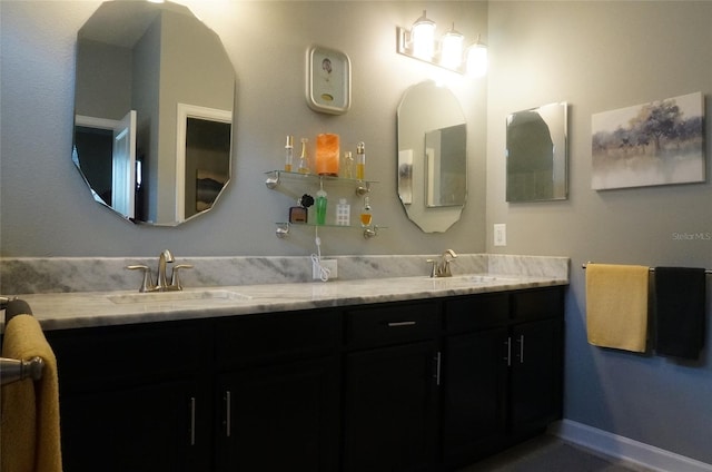 full bath with double vanity, baseboards, and a sink