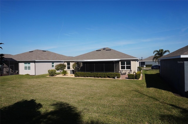 back of house featuring a yard, stucco siding, and a sunroom