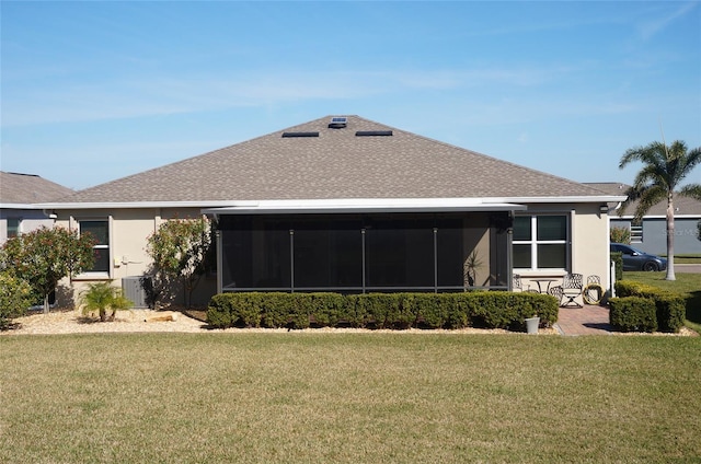 back of house featuring stucco siding, a lawn, roof with shingles, and a sunroom