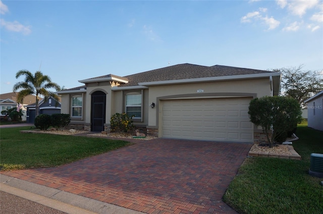 view of front facade with an attached garage, stucco siding, a front lawn, stone siding, and decorative driveway