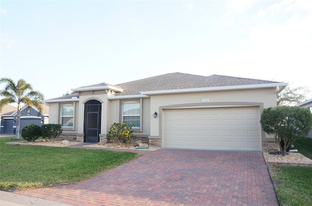 ranch-style house featuring a front lawn, stucco siding, decorative driveway, stone siding, and an attached garage