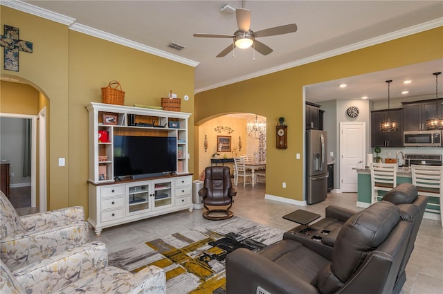 living room featuring arched walkways, ornamental molding, baseboards, and ceiling fan with notable chandelier