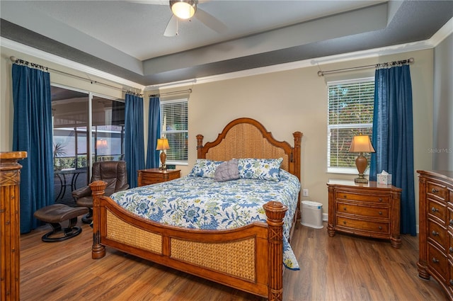 bedroom with ornamental molding, a raised ceiling, access to exterior, a ceiling fan, and wood finished floors