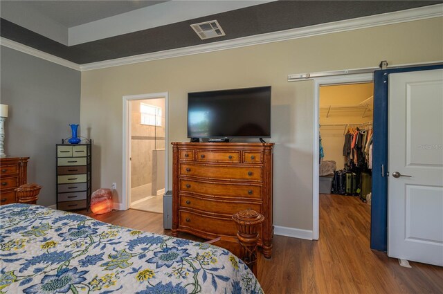 bedroom with a closet, visible vents, a spacious closet, and wood finished floors