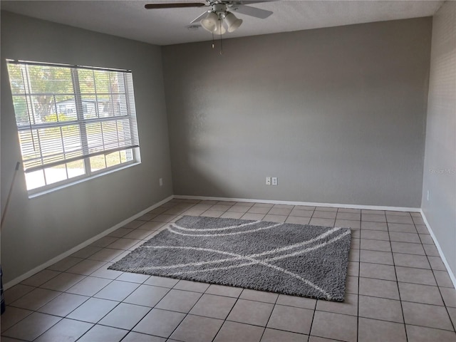 tiled empty room featuring ceiling fan and plenty of natural light