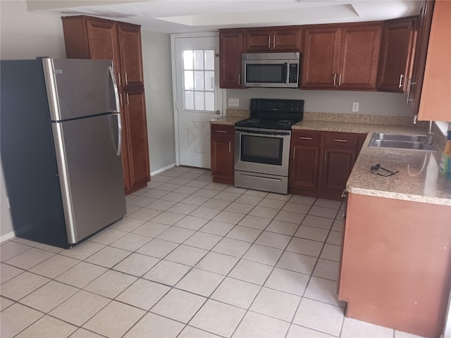 kitchen featuring sink, light tile patterned flooring, a raised ceiling, and appliances with stainless steel finishes