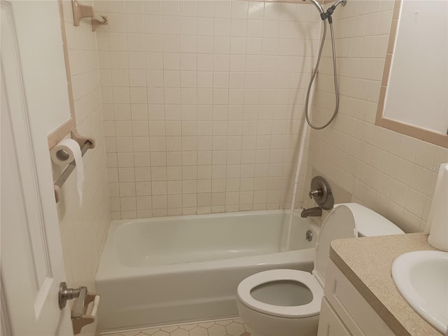 full bathroom featuring tile walls, tiled shower / bath combo, vanity, tile patterned flooring, and toilet