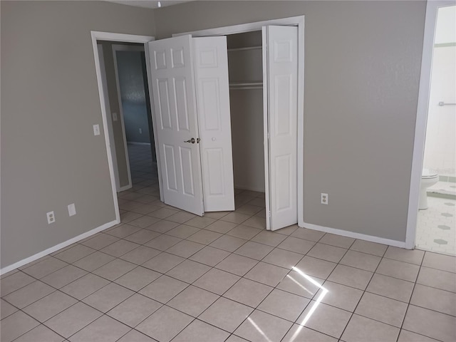 unfurnished bedroom with connected bathroom, light tile patterned floors, and a closet