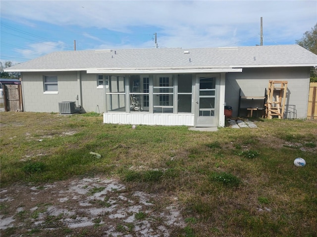 rear view of property featuring a sunroom, a yard, and central AC