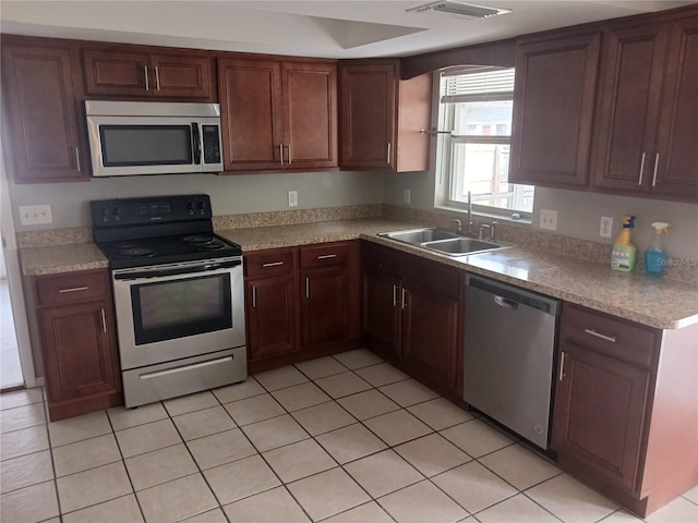 kitchen with appliances with stainless steel finishes, sink, and light tile patterned floors