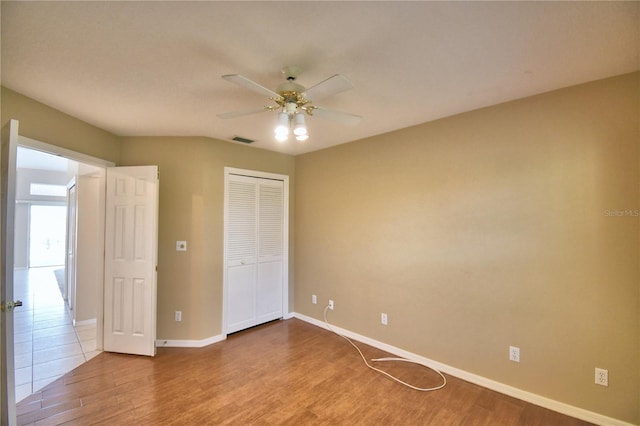 unfurnished bedroom featuring hardwood / wood-style floors, a closet, and ceiling fan