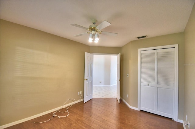 unfurnished bedroom with hardwood / wood-style flooring, a closet, and ceiling fan