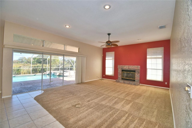 unfurnished living room with a high end fireplace, light colored carpet, and ceiling fan