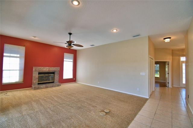 unfurnished living room with light tile patterned flooring, ceiling fan, and a high end fireplace