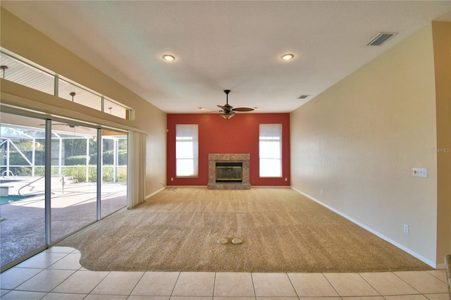 unfurnished living room featuring a tiled fireplace, light tile patterned floors, and ceiling fan