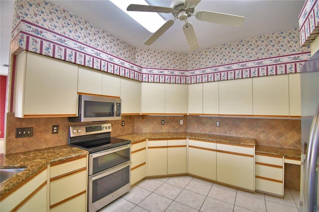 kitchen with light tile patterned flooring, ceiling fan, stainless steel appliances, and cream cabinetry