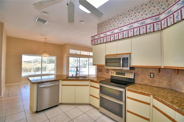 kitchen featuring sink, tasteful backsplash, kitchen peninsula, stainless steel appliances, and cream cabinetry