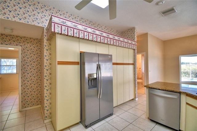 kitchen with light tile patterned floors, stainless steel appliances, ceiling fan, and stone counters