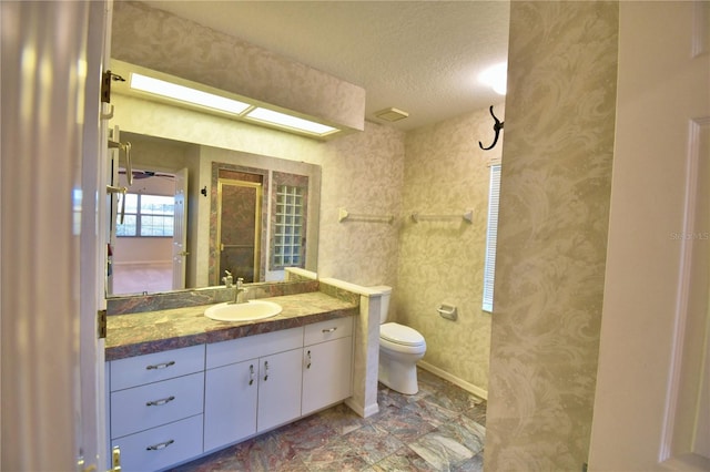 bathroom with vanity, toilet, and a textured ceiling