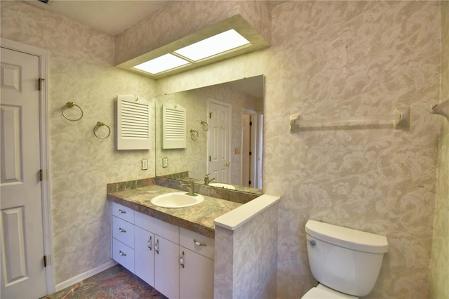 bathroom with vanity, toilet, and a skylight