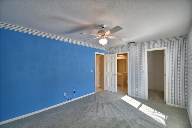 unfurnished bedroom with carpet floors, a walk in closet, ceiling fan, a textured ceiling, and a closet