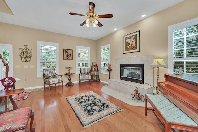 living room with hardwood / wood-style flooring, ceiling fan, and a high end fireplace