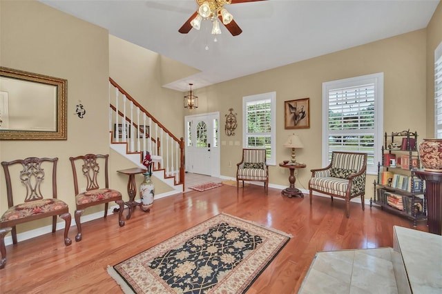 living area featuring ceiling fan with notable chandelier and hardwood / wood-style floors