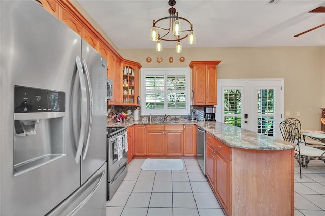 kitchen featuring light tile patterned flooring, decorative light fixtures, tasteful backsplash, sink, and stainless steel appliances