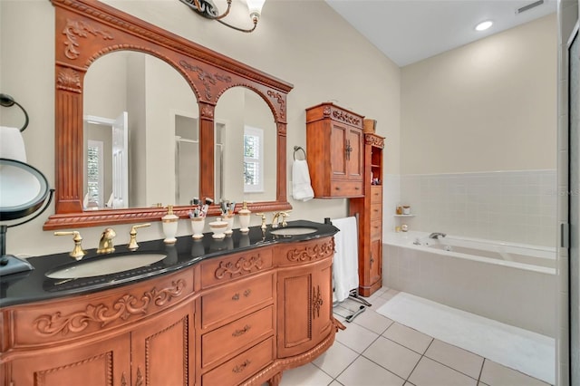 bathroom with tile patterned flooring, vanity, and tiled tub