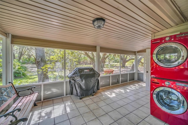 laundry room with tile patterned flooring and stacked washing maching and dryer