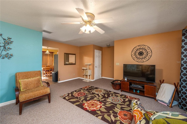 living room with ceiling fan, carpet flooring, and a textured ceiling