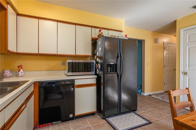 kitchen with white cabinetry, light tile patterned floors, sink, and black appliances