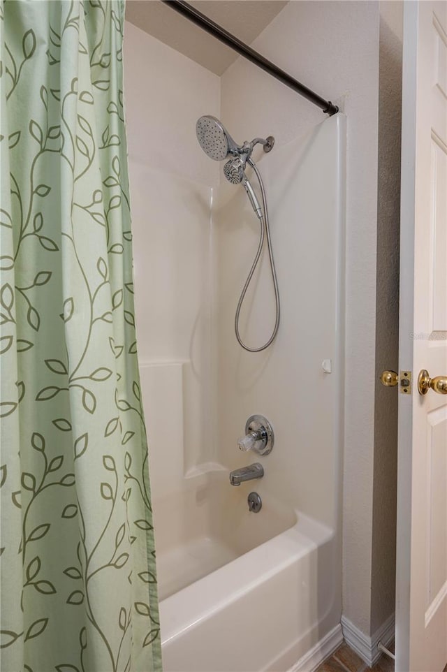 bathroom with shower / tub combo and baseboards