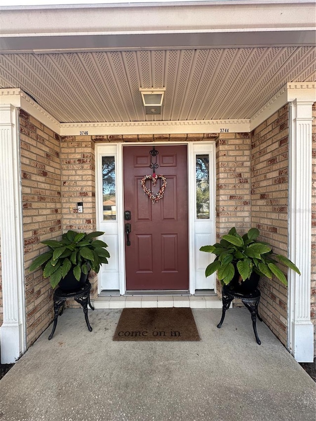 entrance to property with covered porch and brick siding